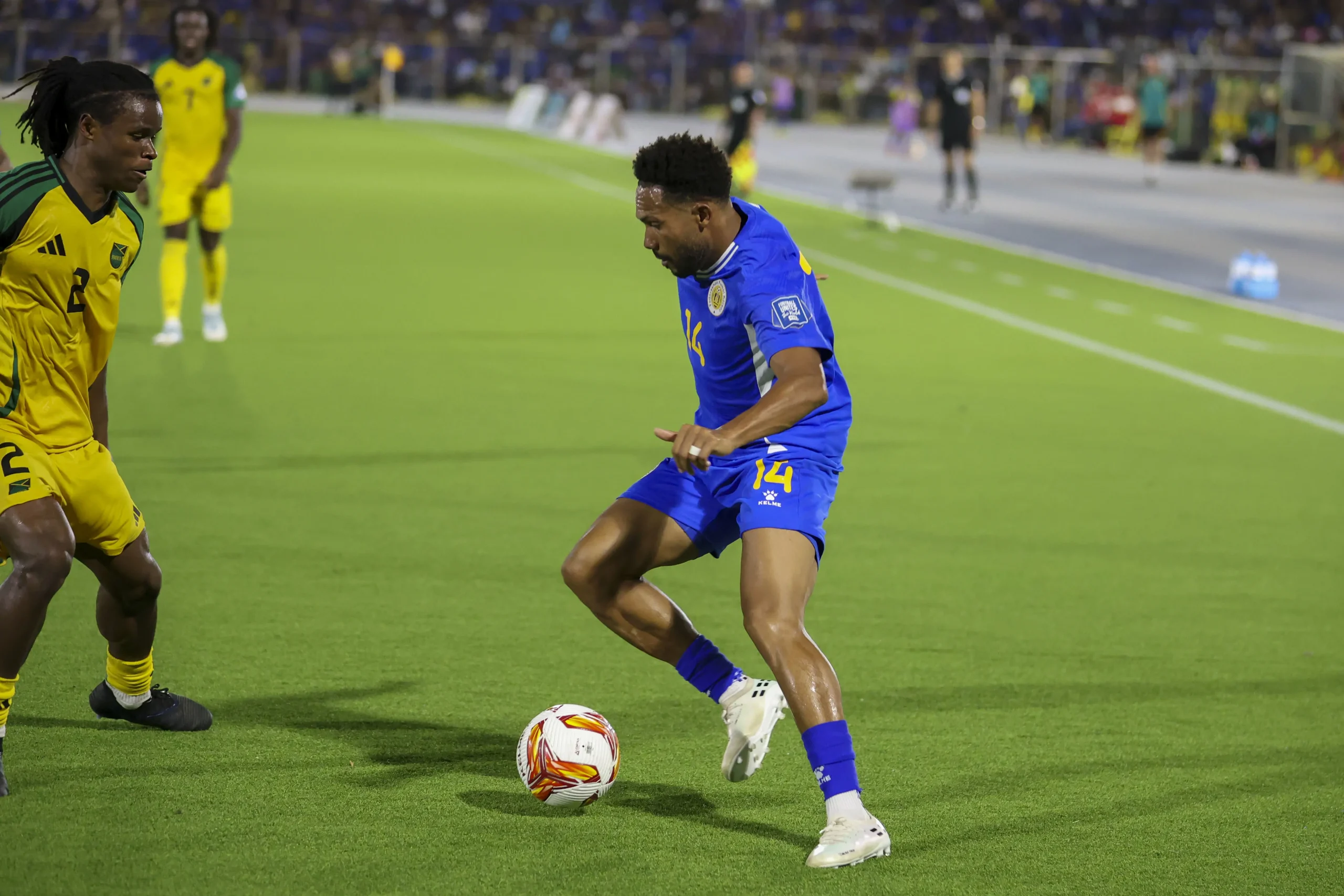 Kenji Gorré (14) intenta eludir a Dexter Lembikisa de los Reggae Boys. De fondo observa Demarai Gray.